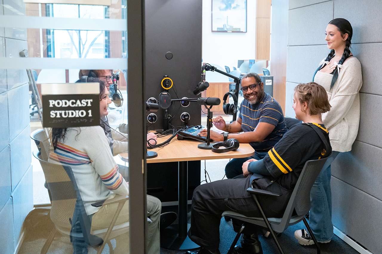 A group of students gathers in a podcast recording studio.